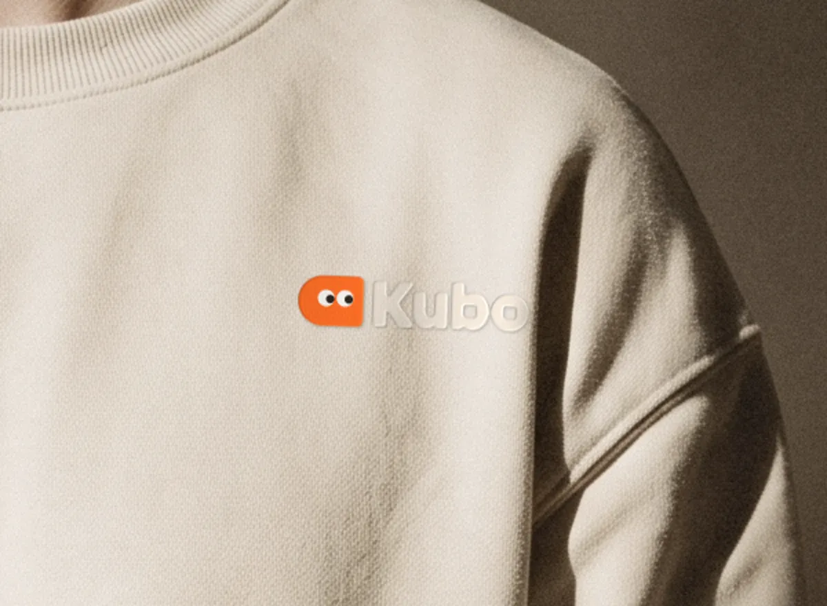 The lockup on the crewneck's chest, close up: the orange mark and a tone-on-tone wordmark