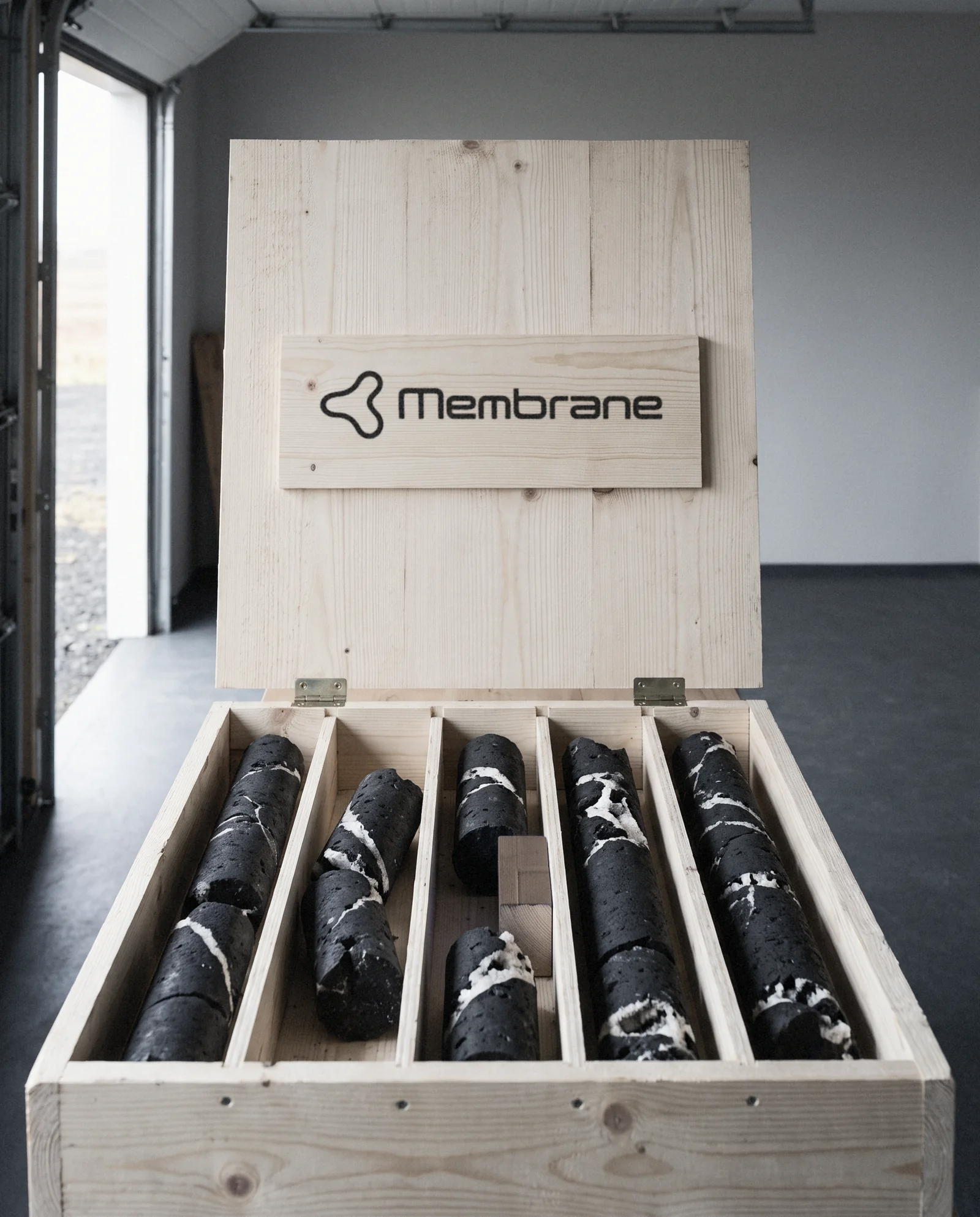 A pine core crate with the Membrane logo stencilled on the lid, basalt cores inside