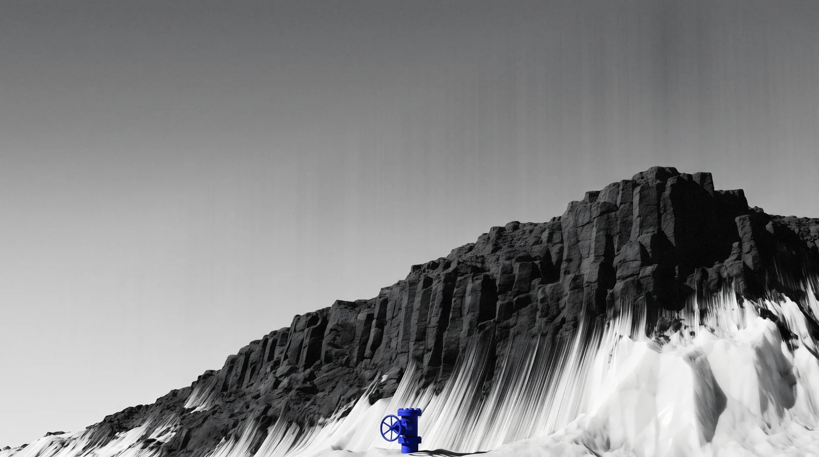 A black basalt ridge whose lower slopes have turned to white crystal, a small ultramarine wellhead at its foot