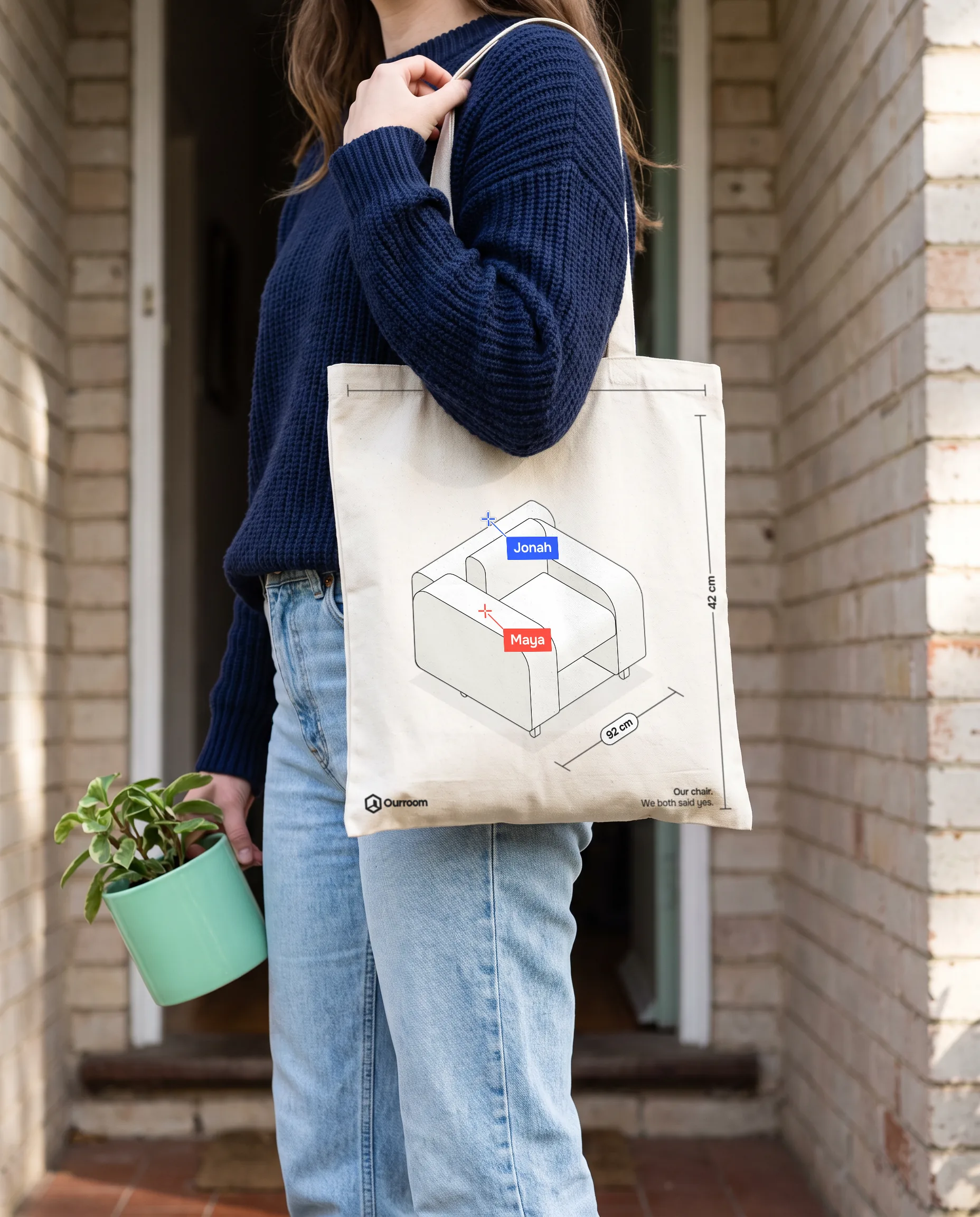 A person carrying the Ourroom tote on moving day: the armchair in line, both cursors and a 92 cm dimension
