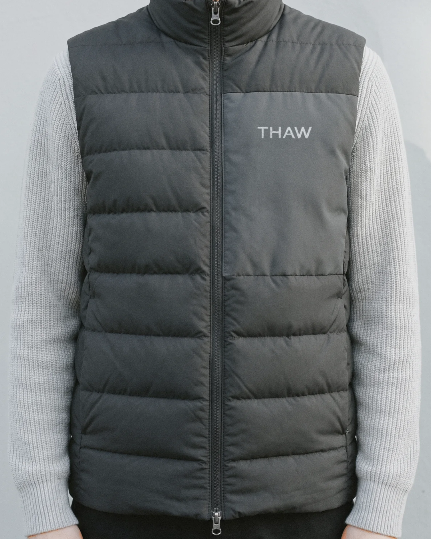 A graphite vest with the Thaw wordmark